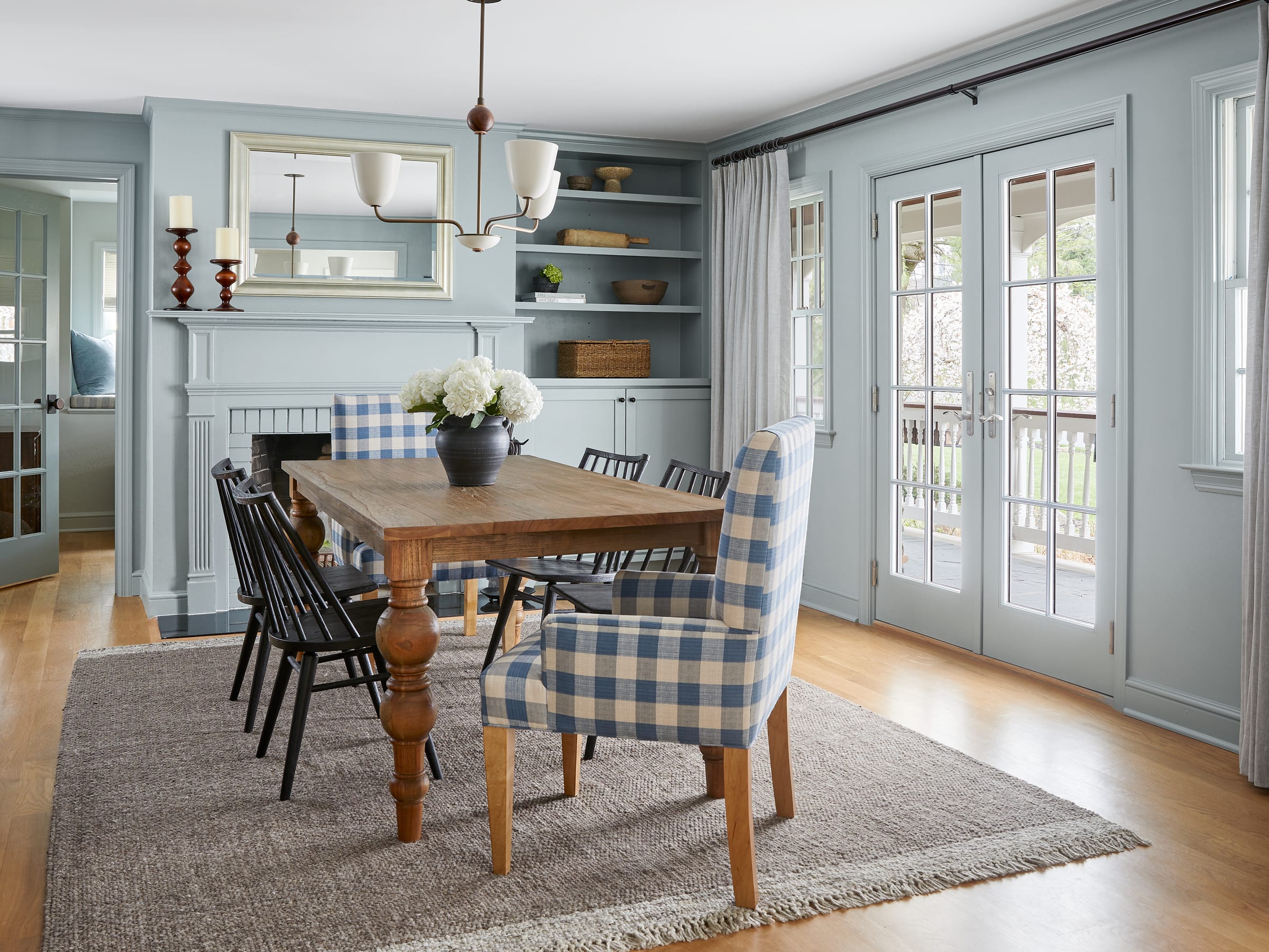 Dining room with a wood table, upholstered chairs and layered lighting in a Westfield, NJ home by Ellie Mroz Design.