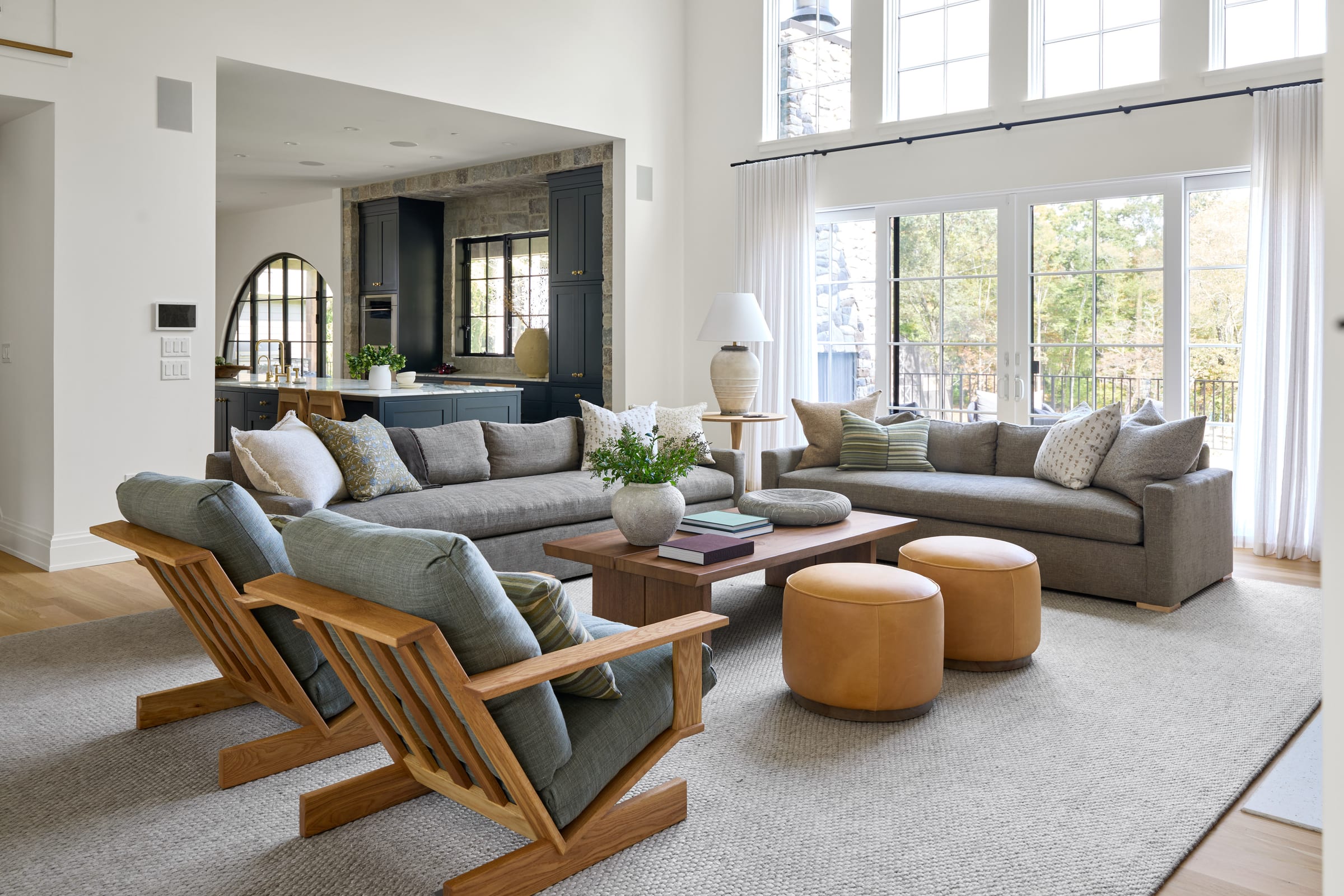 Light-filled family room with layered neutral seating, natural textures and tall windows in a New Jersey home by Ellie Mroz Design.