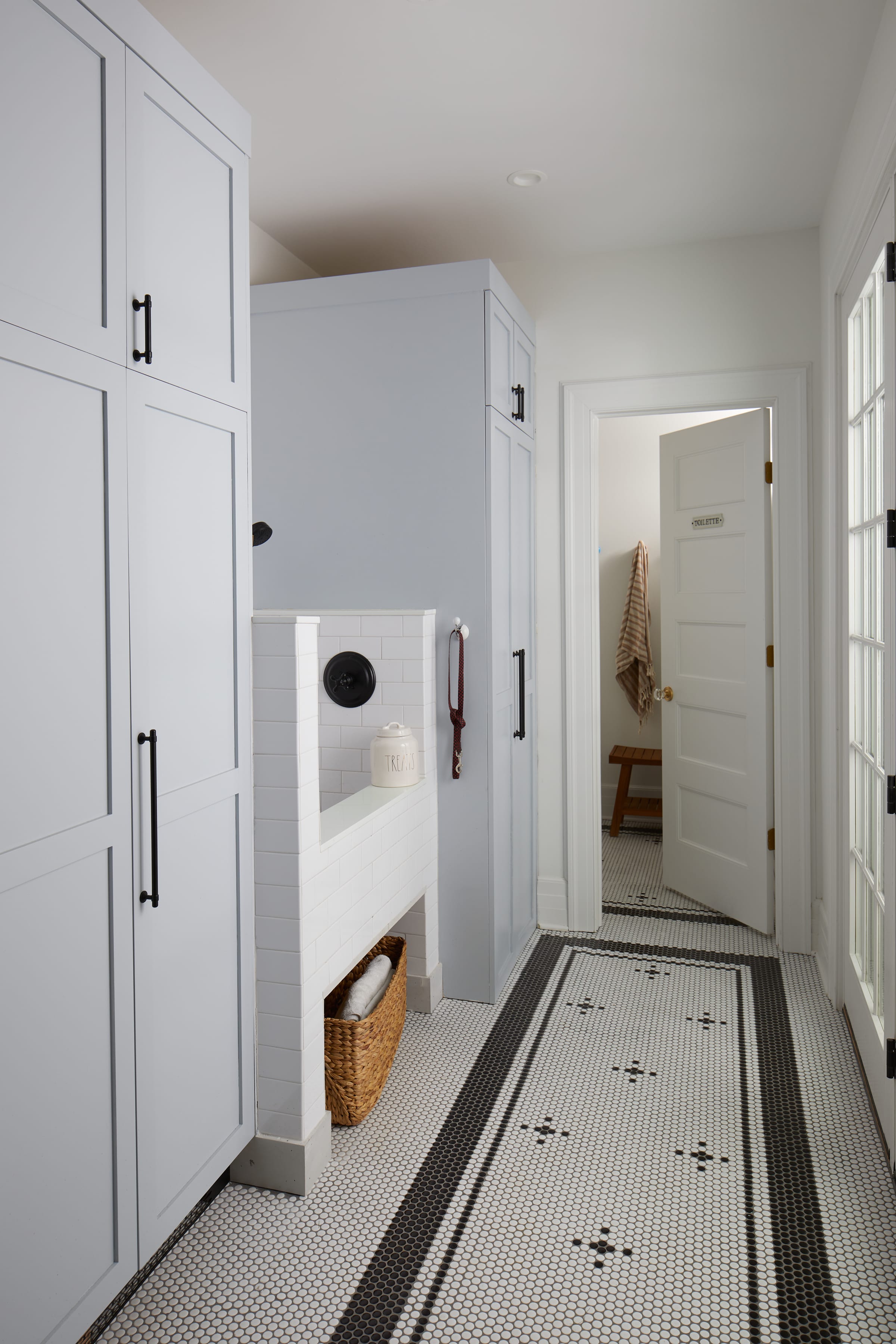 Dog wash station tucked into pale blue custom mudroom cabinetry, with a mosaic tile runner floor, in a 1905 Westfield, New Jersey home renovated by Ellie Mroz Design.