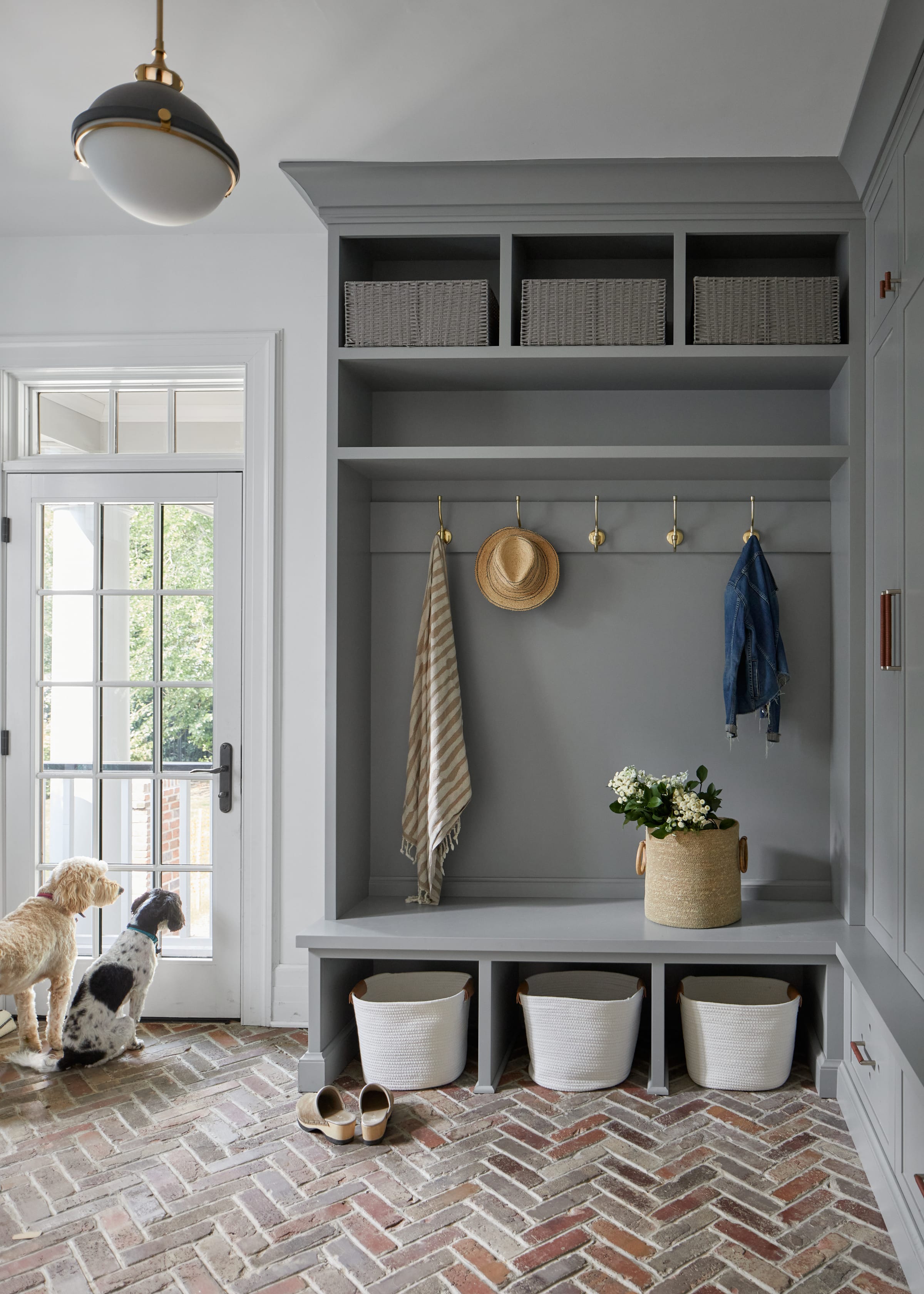 Mudroom with custom built-in storage and herringbone brick floors and dogs in historic Westfield NJ home.