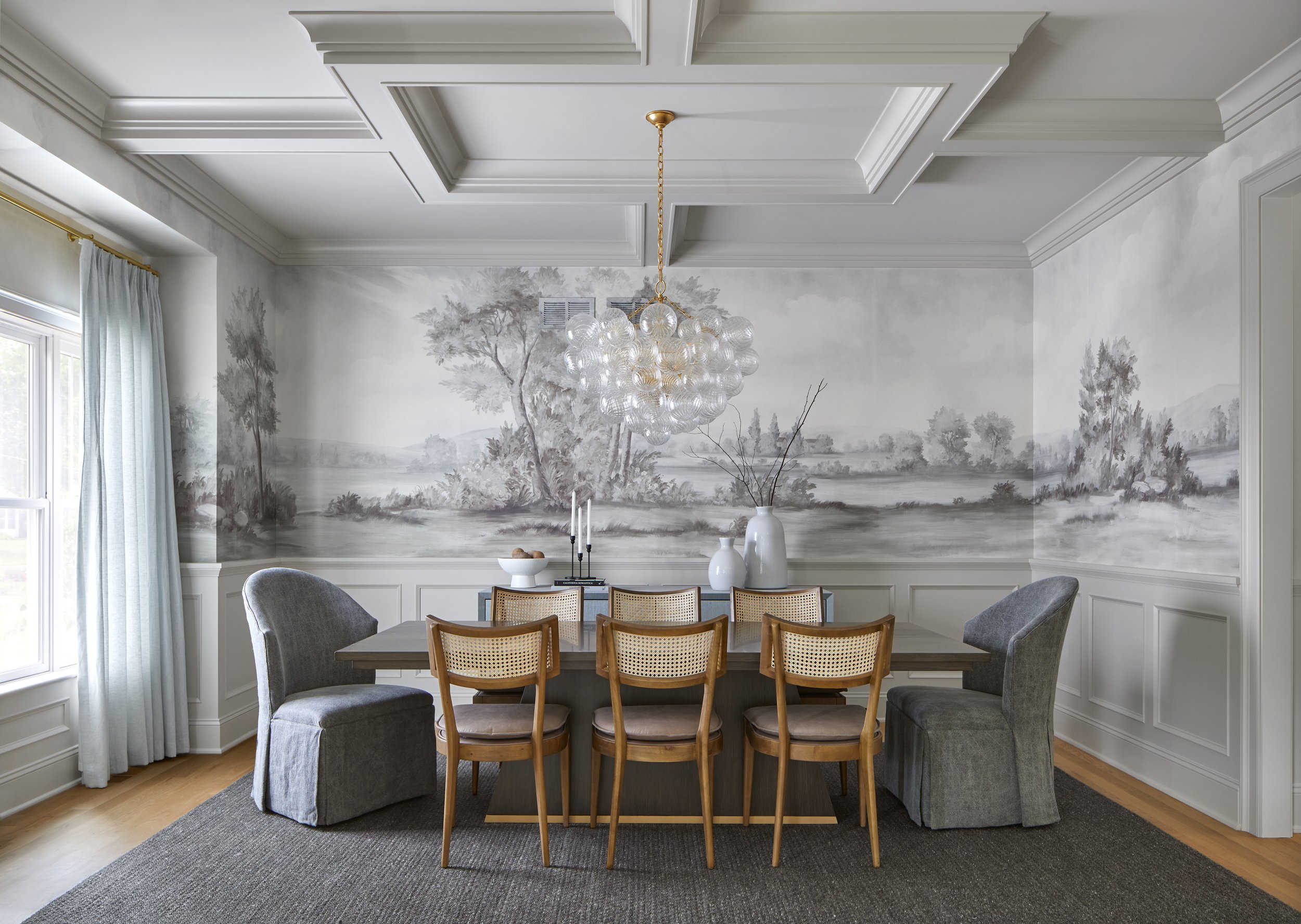 Dining room with hand-painted mural wallpaper and cane-back chairs in a Chatham, New Jersey home by Ellie Mroz Design.