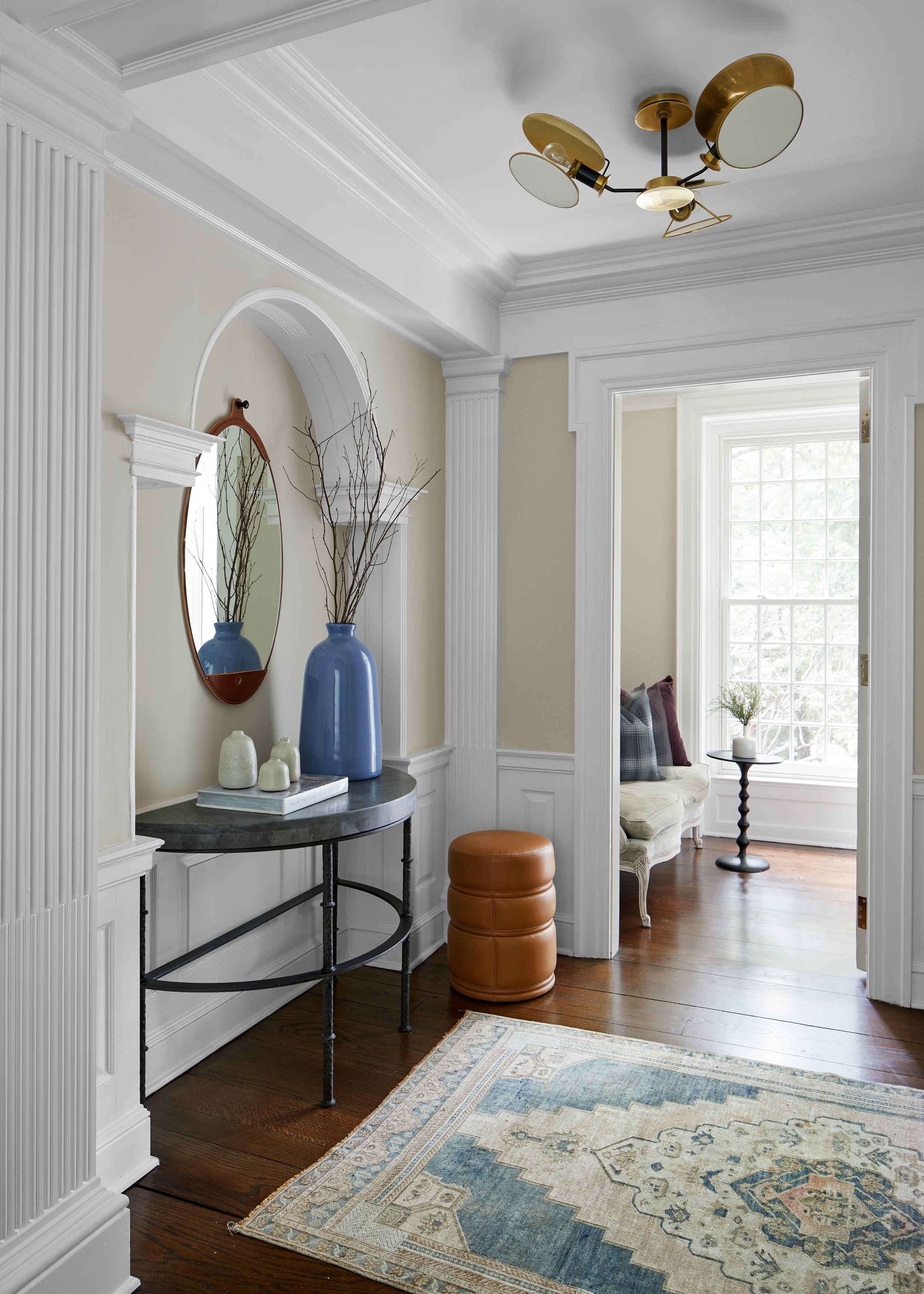 Paneled front entry with a console, mirror and blue vases in a Westfield, New Jersey 1929 home renovation by Ellie Mroz Design.