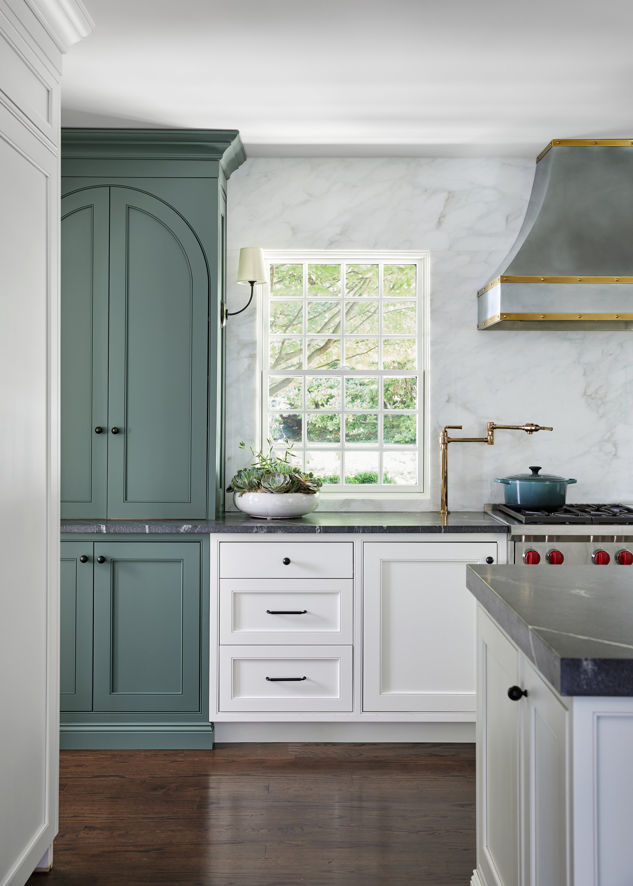 Arched sage green cabinetry with brass hardware in a Westfield, New Jersey kitchen renovation by Ellie Mroz Design.