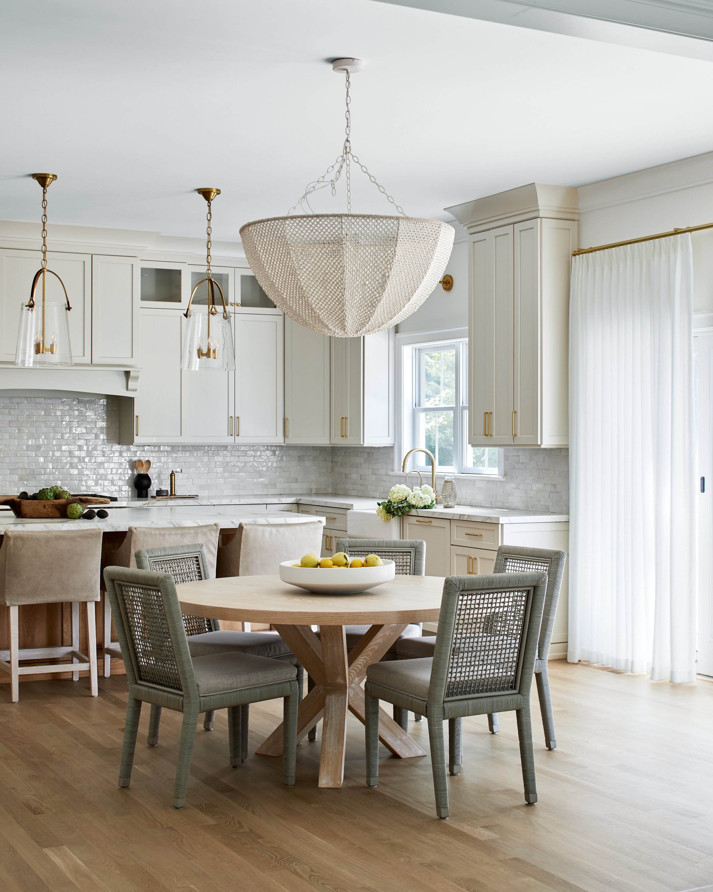 White kitchen with a marble island and a beaded chandelier in a Chatham, New Jersey home by Ellie Mroz Design.