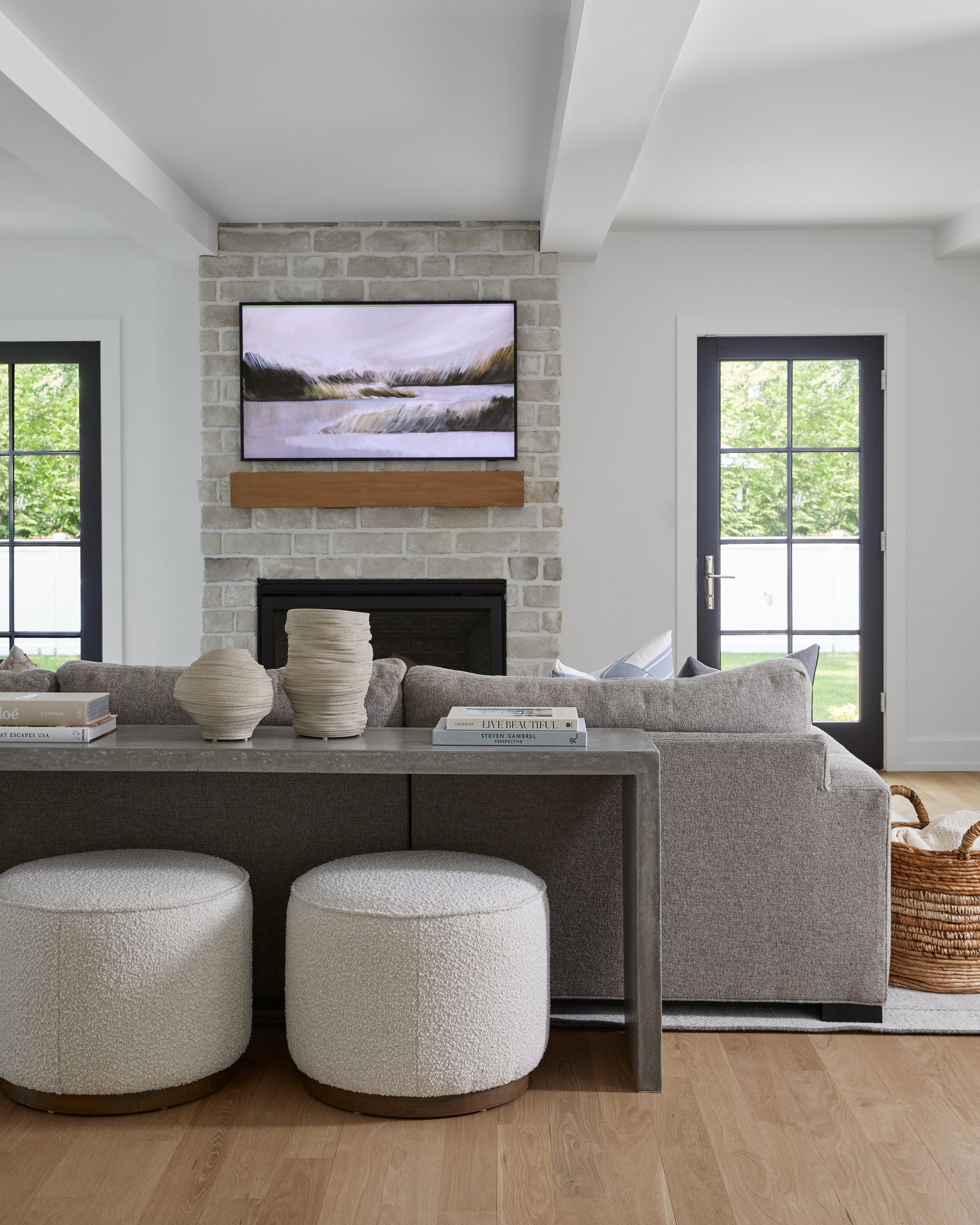 Family room with a whitewashed brick fireplace, floating mantel and gray sectional in a Westfield, New Jersey home renovation by Ellie Mroz Design.