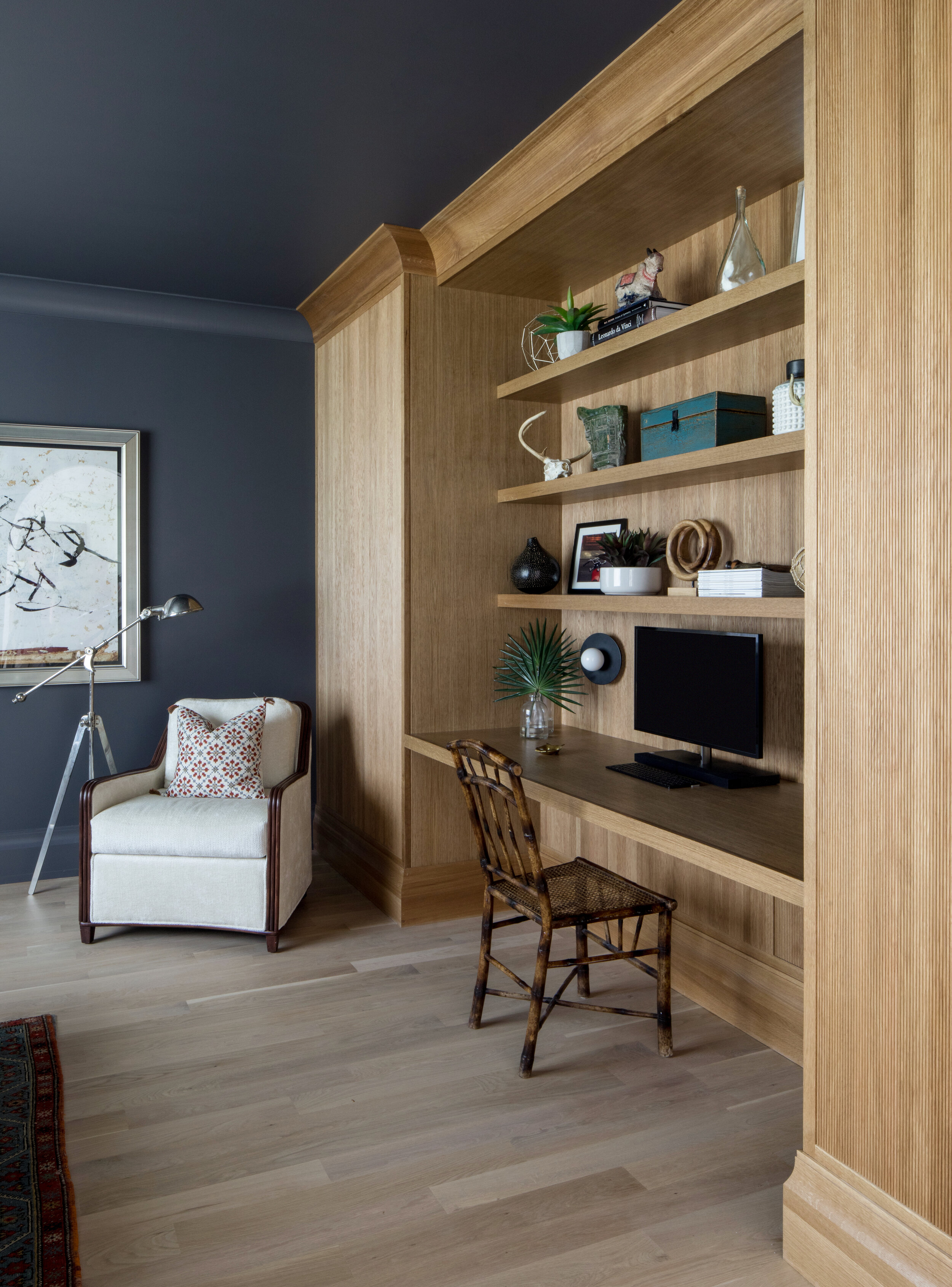 Home office with a built-in oak desk, navy walls and styled open shelving in a Westfield, New Jersey custom home by Ellie Mroz Design.