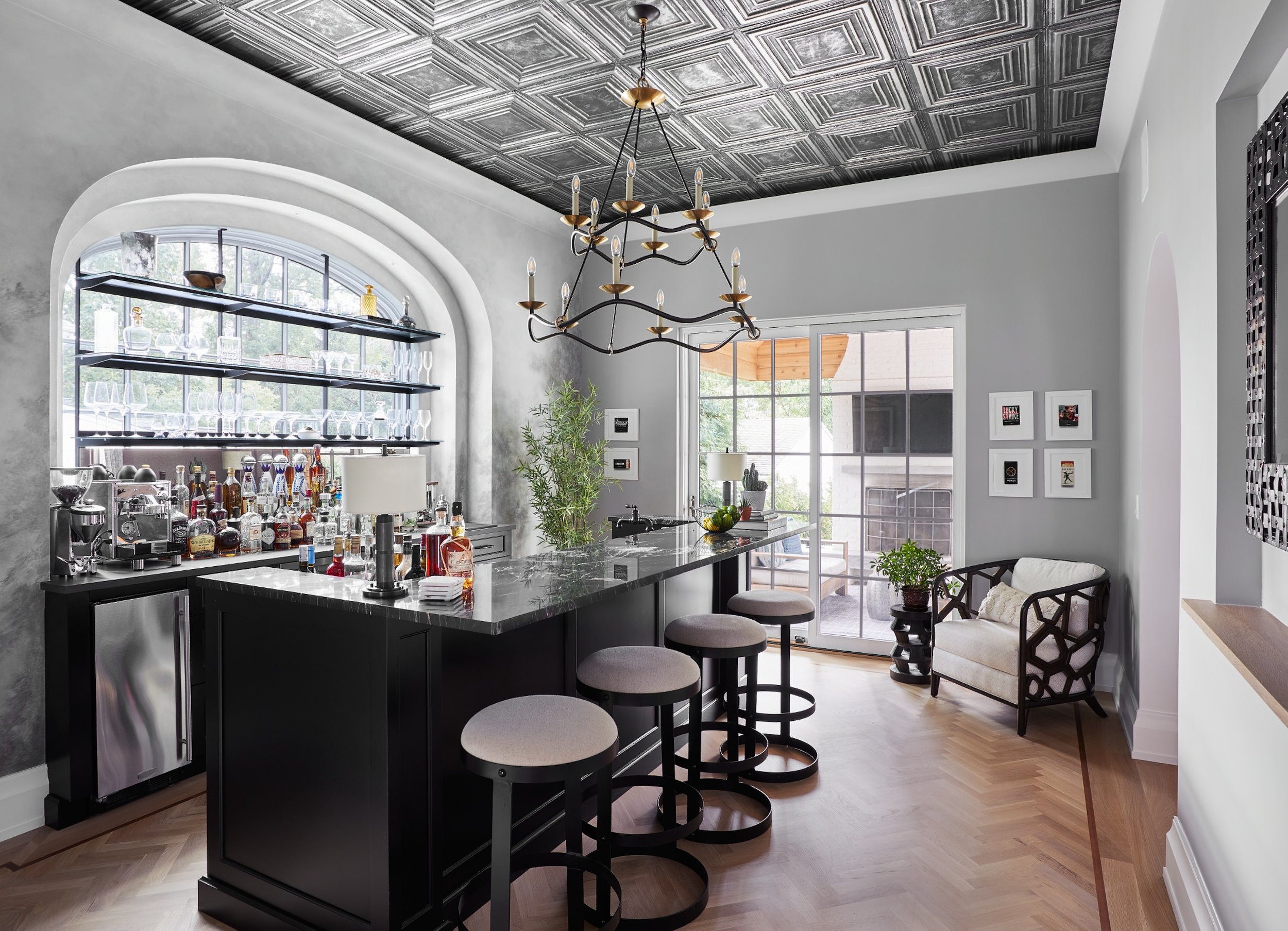 Home pub with a pressed tin ceiling, chandelier and dark bar in a Westfield, New Jersey custom home by Ellie Mroz Design.