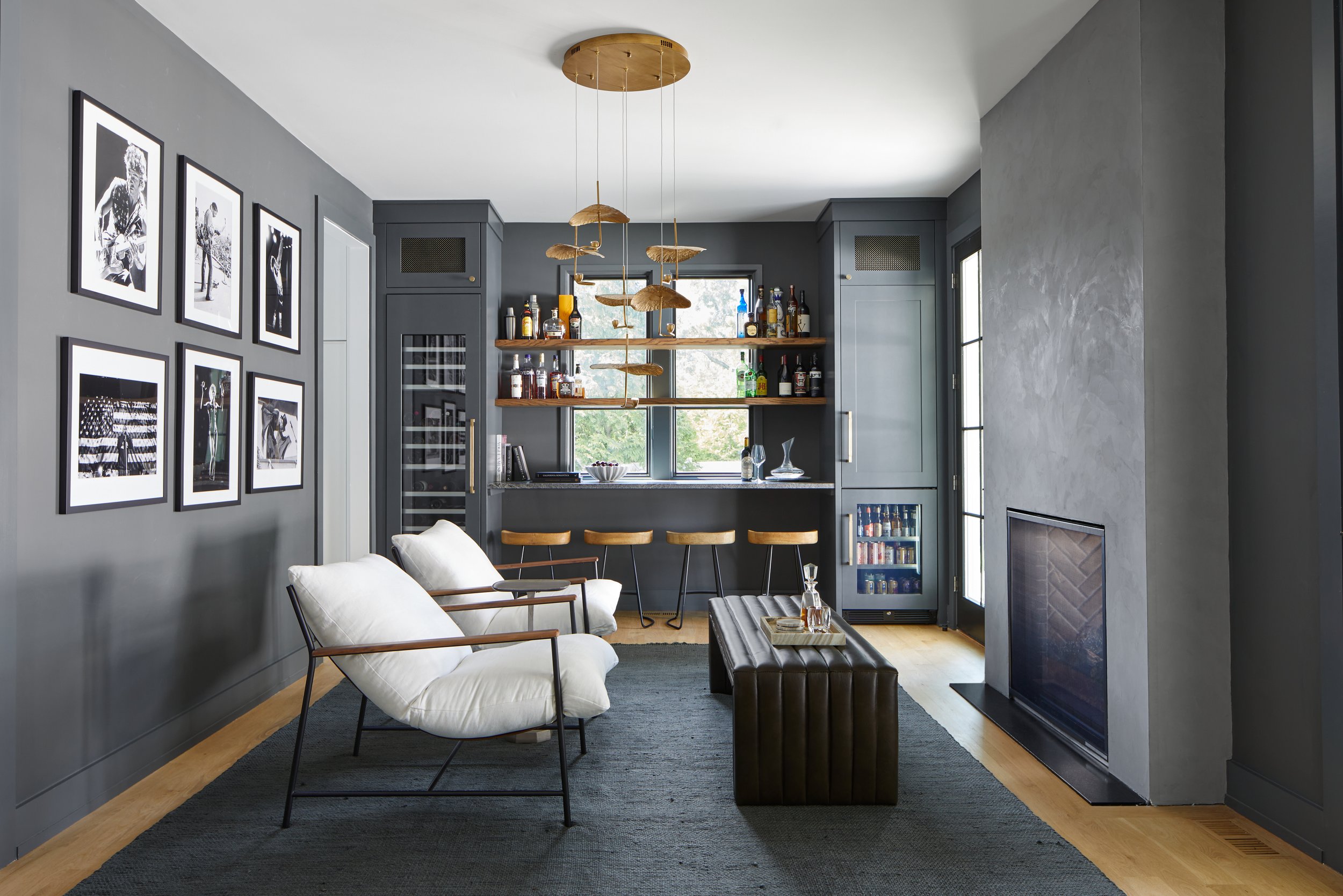 Moody lounge and bar with a gallery wall, custom shelving and a brass pendant in a Westfield, New Jersey home renovation by Ellie Mroz Design.